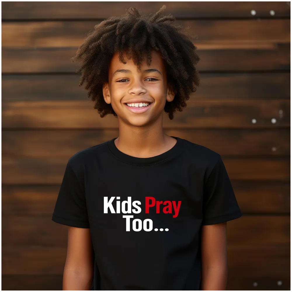 Smiling child wearing a black Kids Pray Too tee